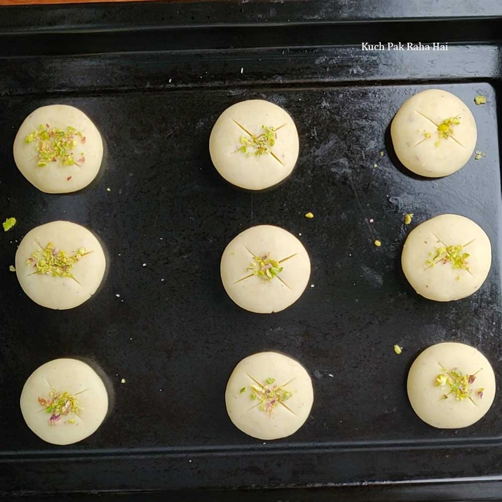 Decorating nankhatai biscuits with chopped pistachios.