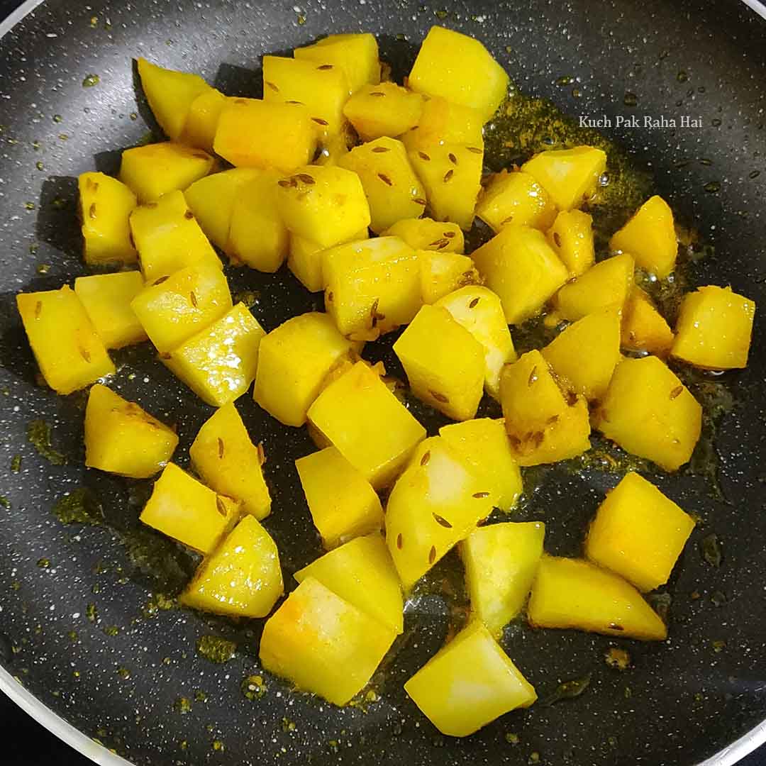 Adding potatoes to the pan with salt & turmeric.