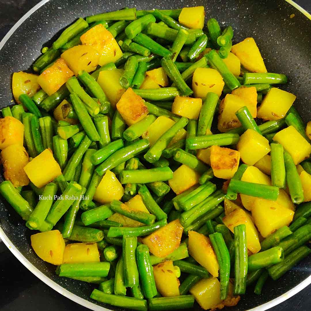 Cooking potato & french beans in a pan.