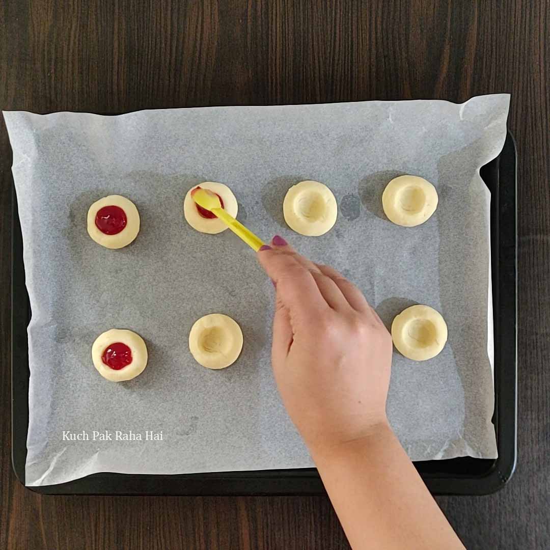 Filling Thumbprint Cookies with jam.