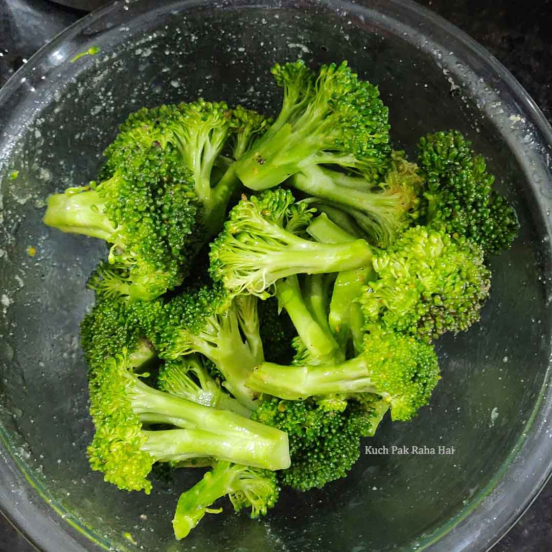 Mixing broccoli with oil and seasoning.