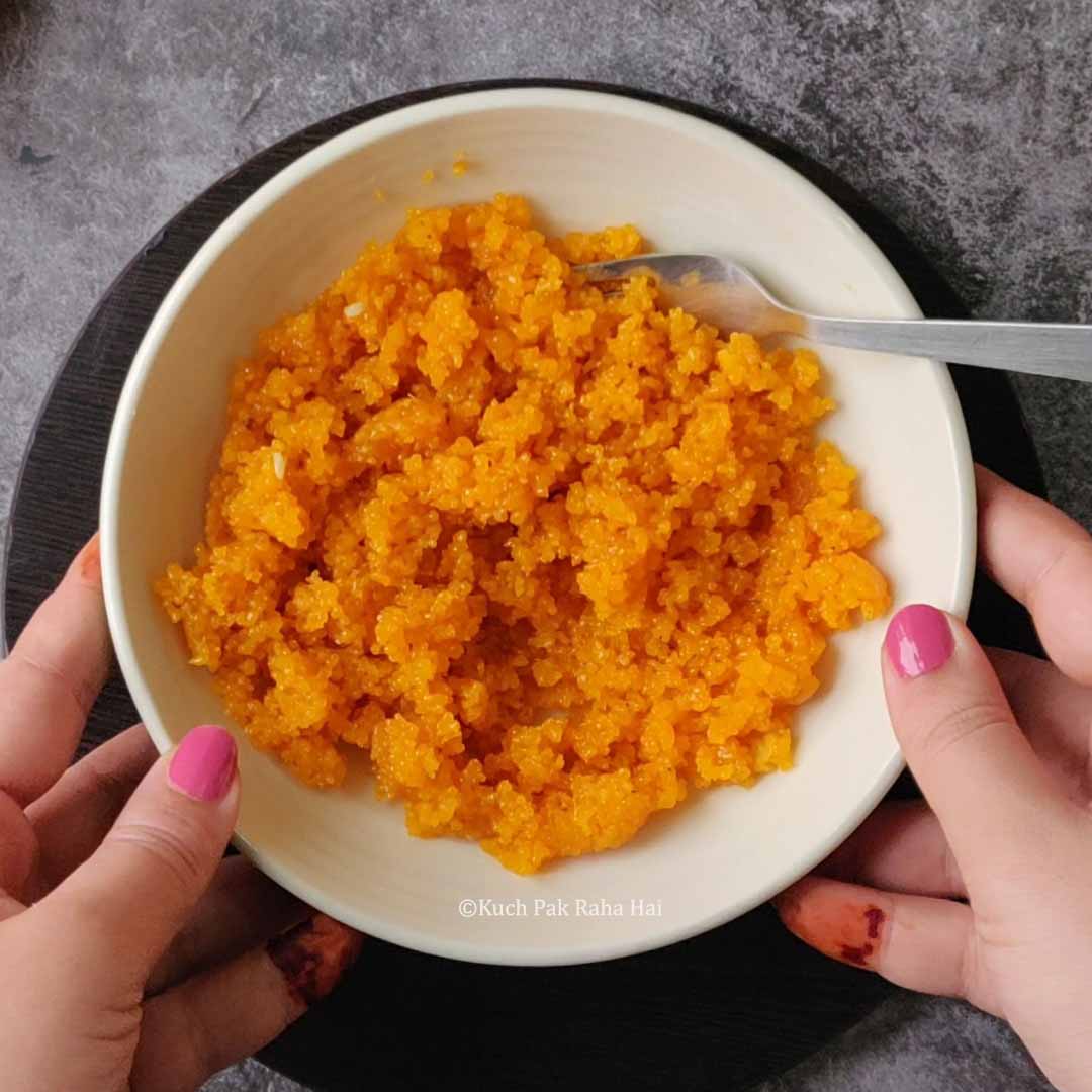 Crumbling motichoor laddu with fork.