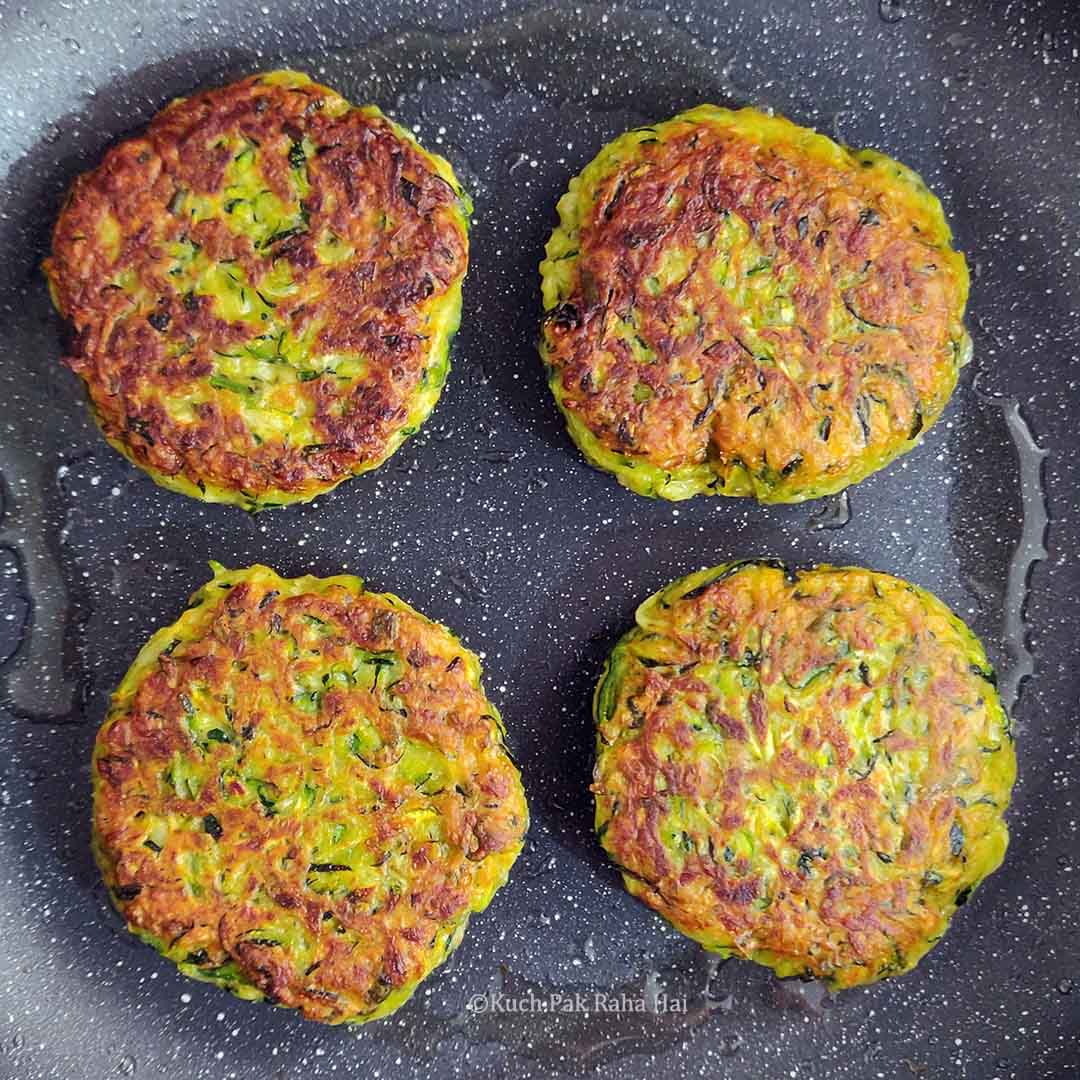 Cooking vegan zucchini fritters in pan.