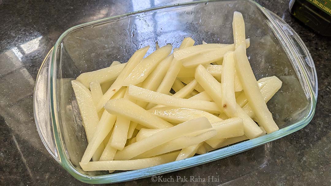 Tossing french fries in olive oil & salt.