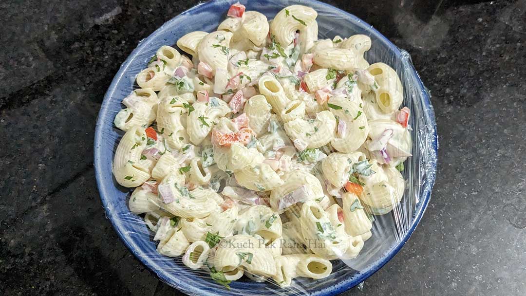 Covering macaroni salad with cling wrap to avoid from drying.