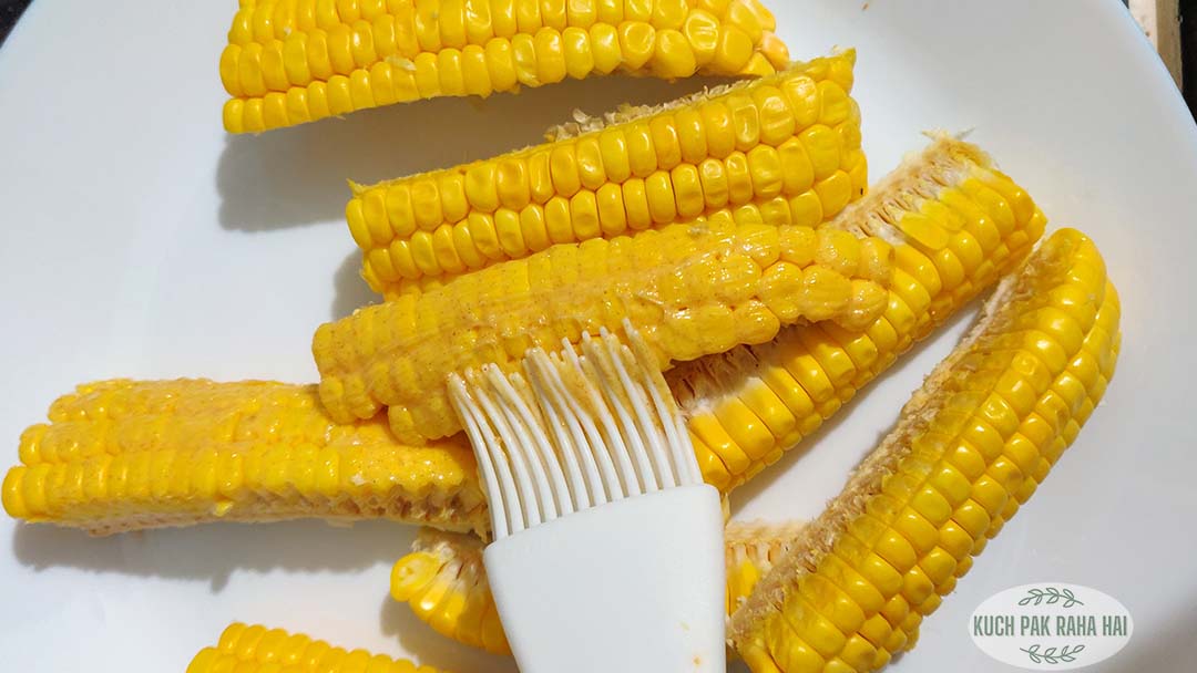 Applying butter on corn ribs.