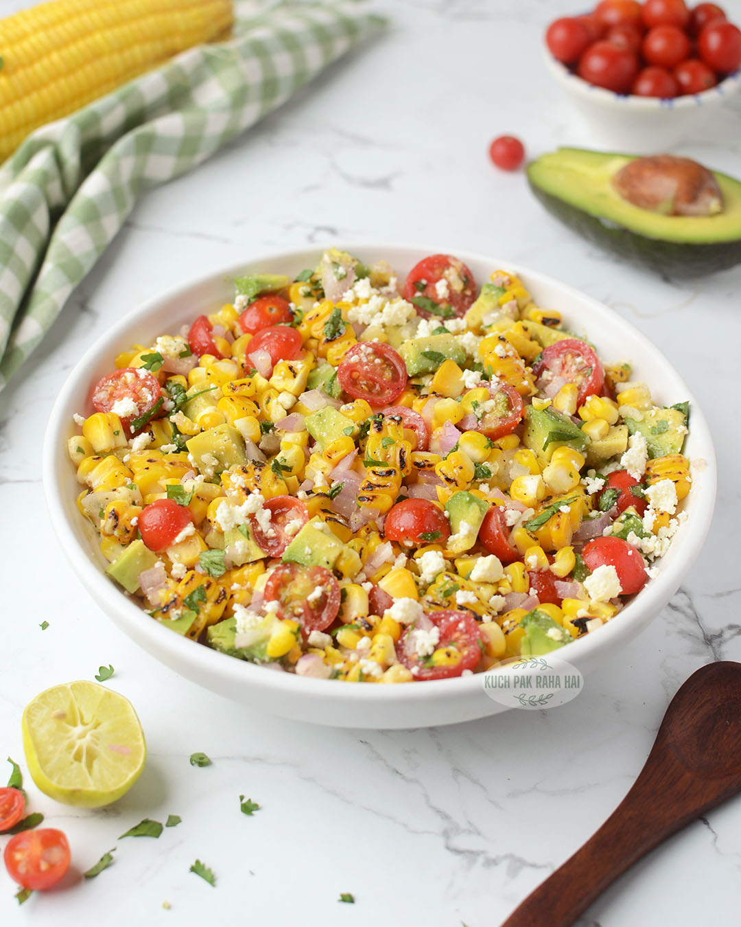 Grilled corn avocado tomato salad with feta lime dressing served in white bowl.