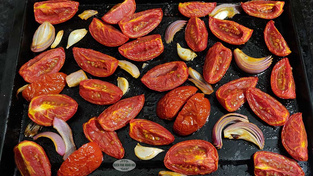 Roasting tomatoes garlic onion on baking tray straight out of oven.