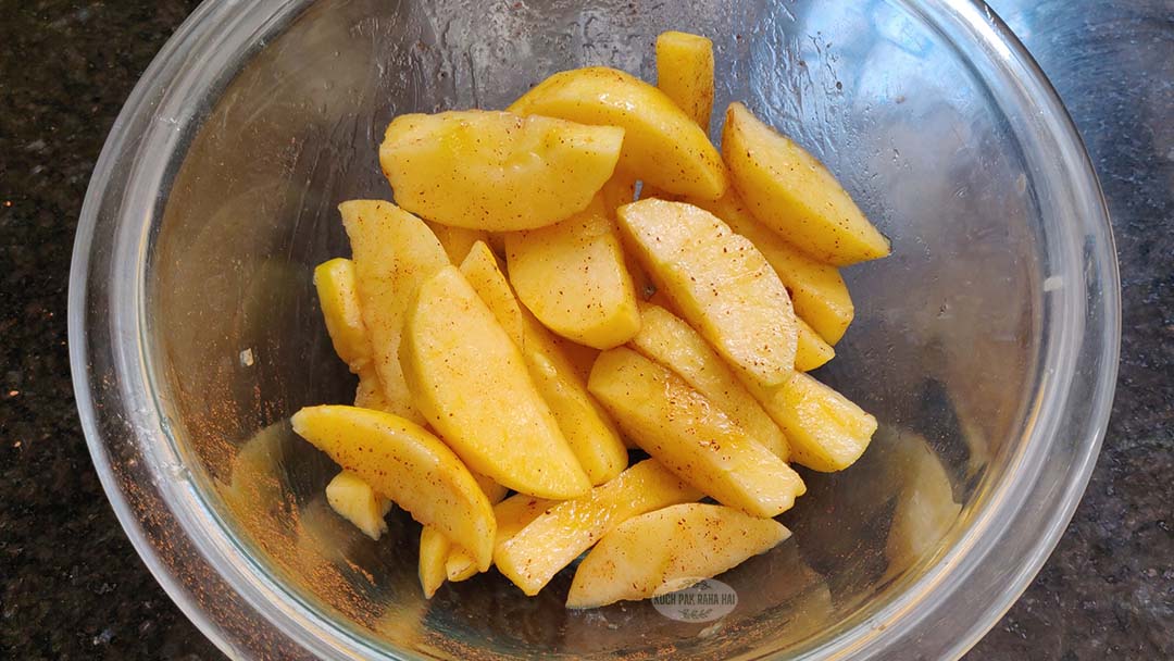 Apples tossed in cinnamon oil in a bowl.