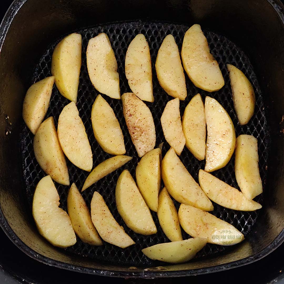 Apples slices arranged in air fryer basket.