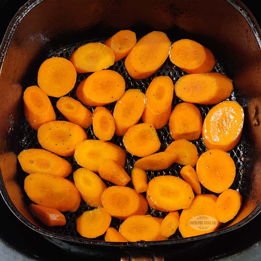 Placing sliced carrots in air fryer.