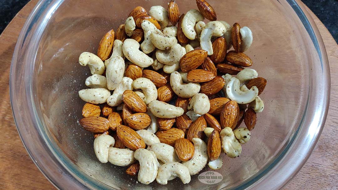 Tossing nuts in oil salt and pepper in a bowl.