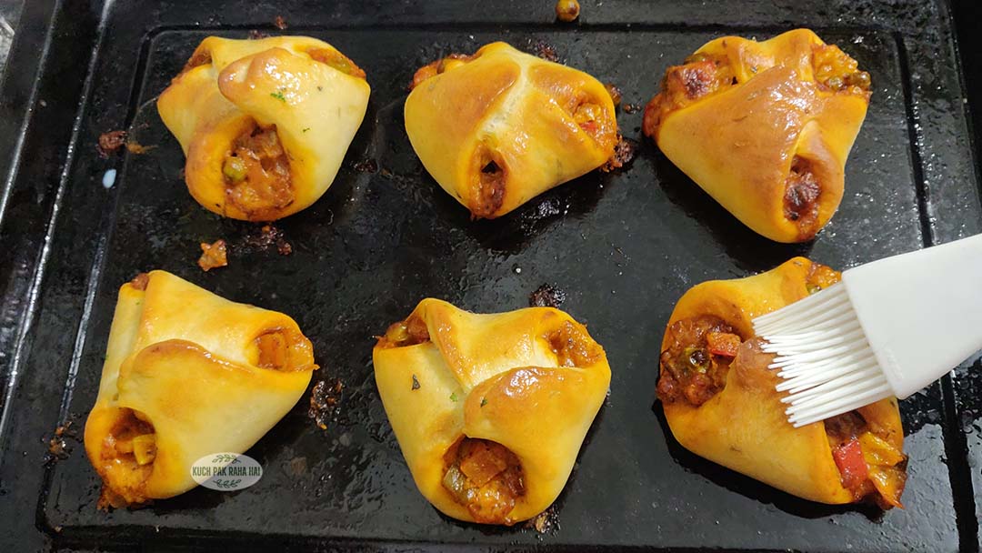 Brushing melted butter on vegetable parcels after baking.