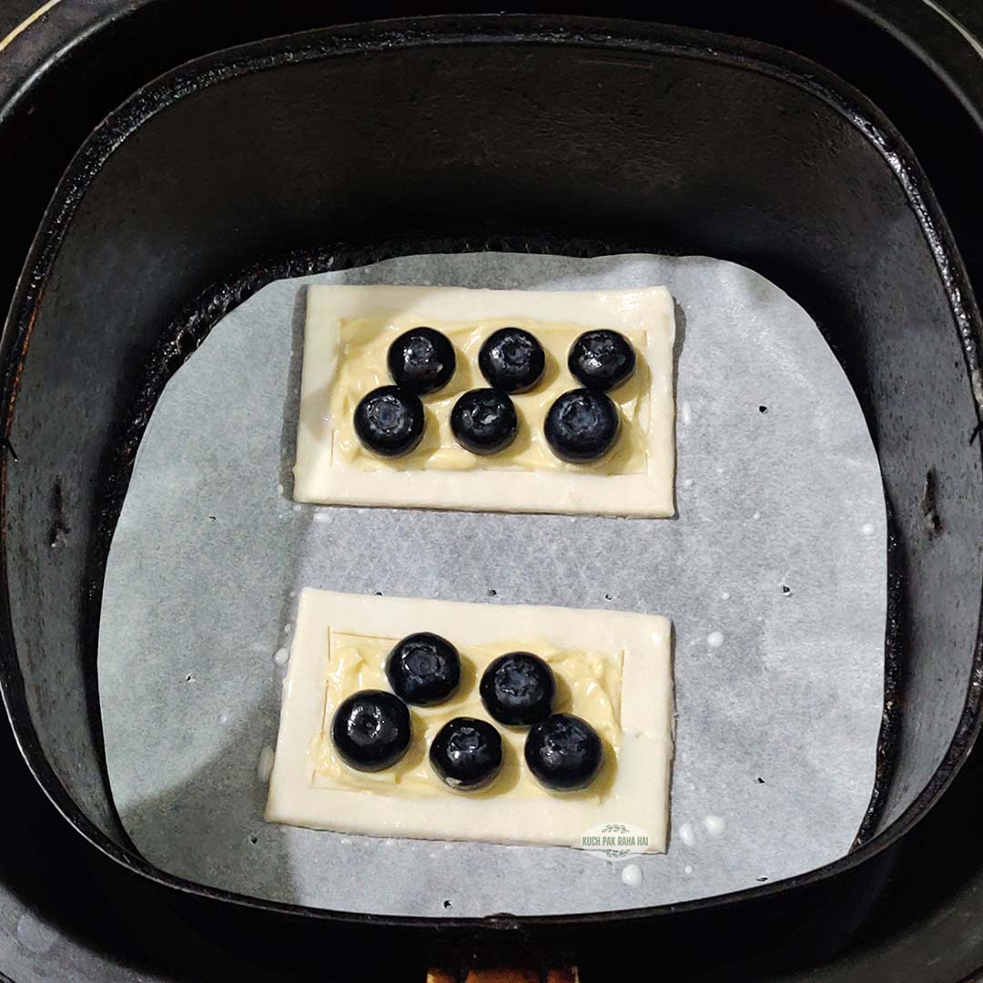 Blueberry puff pastry in air fryer before air frying.