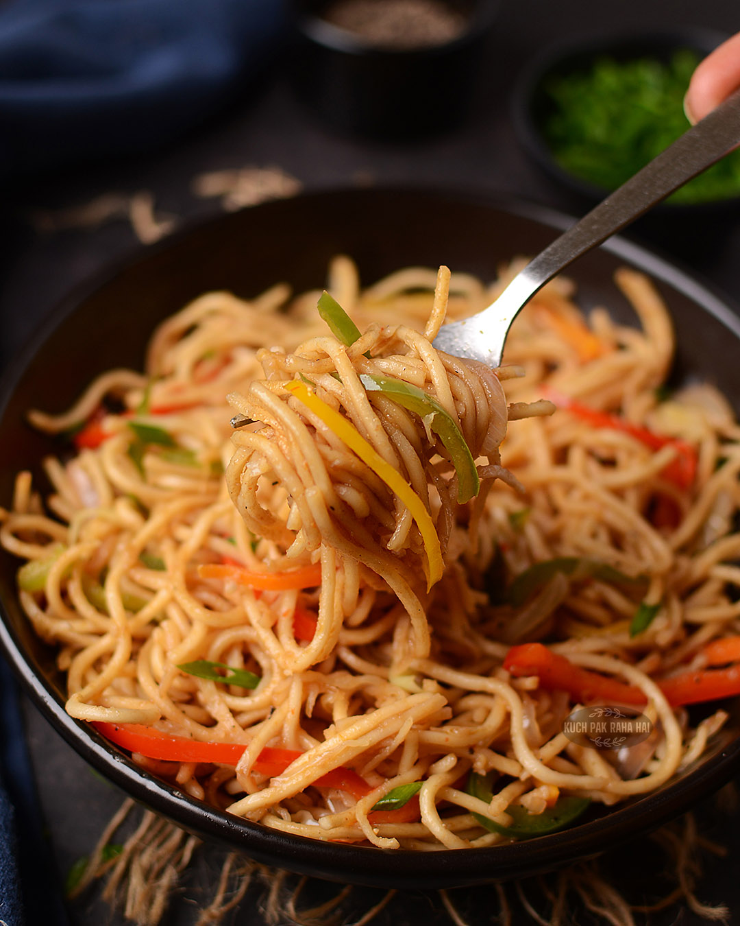 Veg hakka noodles in a black bowl.