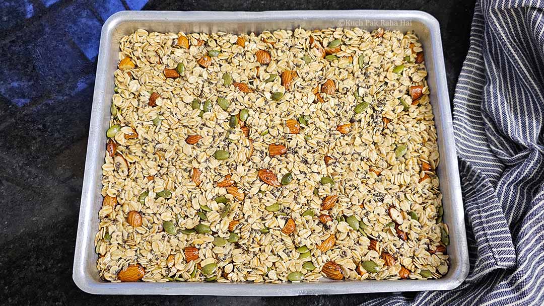 Spreading granola mixture on baking tray.