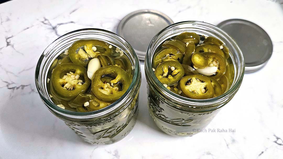 Pickled jalapeno cooling in jar.