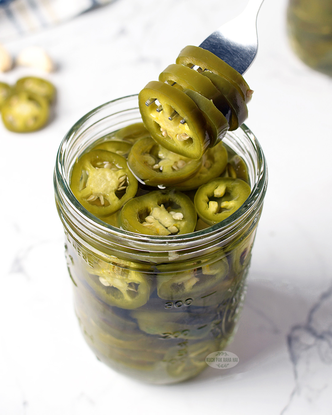 Picking pickled jalapeno slices with a fork.