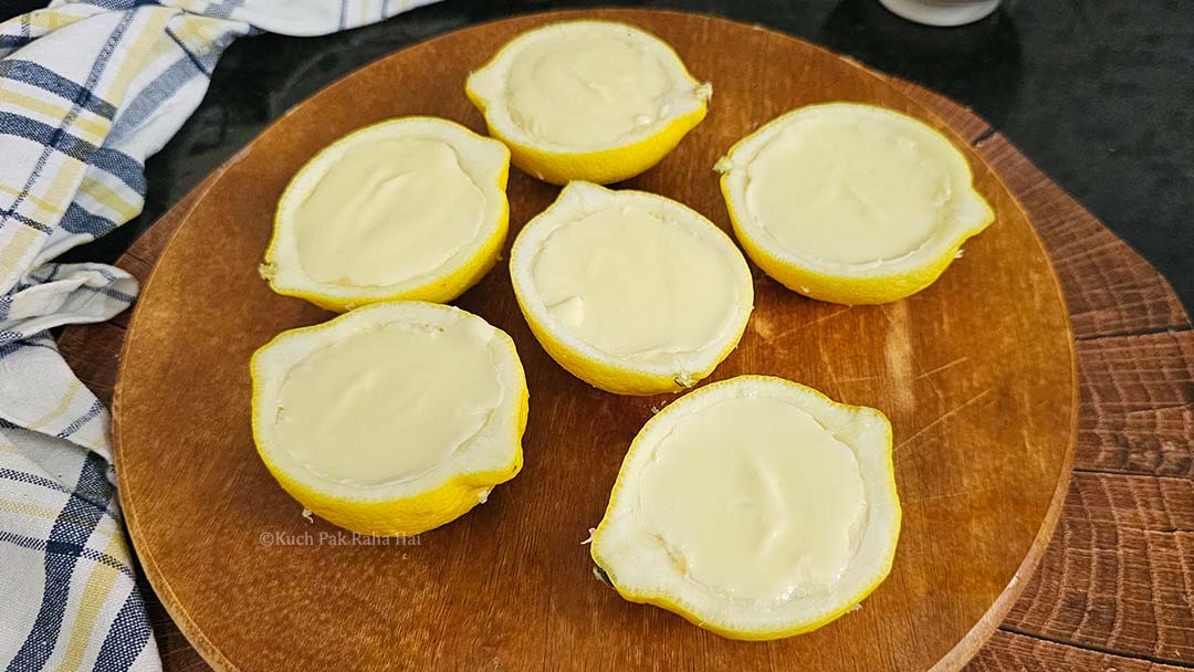 Transferring cream filling in empty lemon peels.